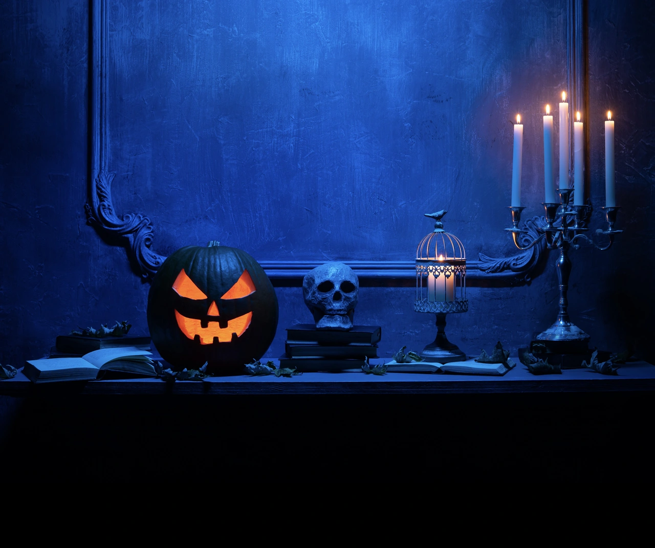 Halloweendekor med pumpa, dödskalle och lykta mot blå vägg